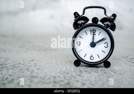 Minimale Miniaturansicht für Wecker, die eine Referenz für die Nachmittagszeit um zwei Uhr mit einer ruhigen, monochromen Tischplatte darstellt. Stockfoto