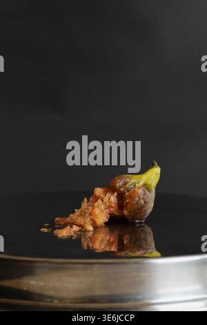 Reif geschnittene Feige auf silbernem reflektierendem Teller vor dunklem Hintergrund. Moody dramatisches Essen still Life Fit Vamp Romantik Trend. Stockfoto