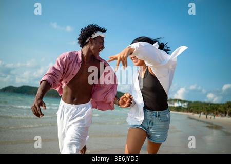Interrassisches Paar, das einen romantischen Strandurlaub genießt und Liebe, Lachen und Zweisamkeit genießt Stockfoto