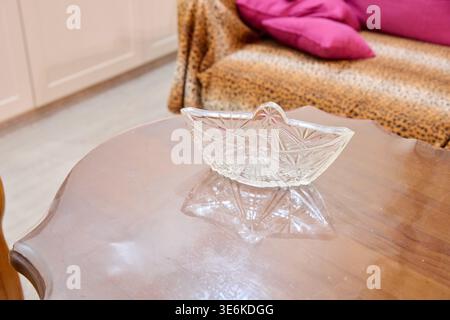 Transparente Glasschale mit komplizierten Sternmustern auf glattem, poliertem Holztisch, warmer Innenbeleuchtung und Hintergrund mit leo Stockfoto