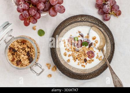 Hausgemachtes Müsli mit Haferflocken, Nüssen, frischen roten Trauben, Rosinen, Minze und Joghurt. Leckeres gesundes Frühstück. Diät. Richtige Ernährung. Auswahl Stockfoto