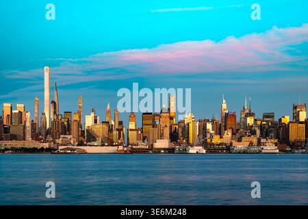 Ein breiter Panoramablick über den Hudson River zeigt die dichte Architektur von Manhattan bei einem farbenfrohen Sonnenuntergang in New York. Stockfoto