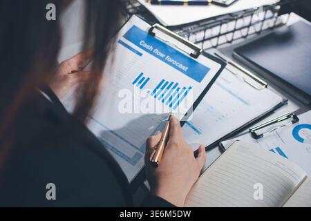 Auditoren arbeiten in modernen Büros zusammen, analysieren Finanzdokumente und verwenden einen Rechner mit einem Laptop, der Diagramme anzeigt. Audit und Steuern im Busine Stockfoto