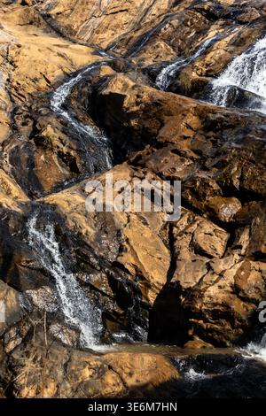 Wasser fließt in Rivurlets auf den glatten, alten Felsen an den Phophonyane Falls, Eswatini Stockfoto