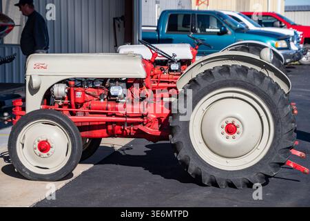 Ford-Traktor in Rot und Creme, der draußen auf einer Messe für Landfahrzeuge geparkt wurde, zeigt klassische Maschinen, große Hinterreifen und freiliegende Motorkomponenten Stockfoto