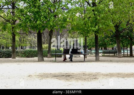 Jardin du Palais Royal, Menschen, die auf einer Bank unter Bäumen sitzen, auf dem historischen Gelände eines Palastes aus dem 17. Jahrhundert, 1. Arrondissement, Paris, Frankreich. Stockfoto