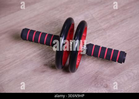 Ein Satz Trainingsrollen sitzt auf einem Holzboden. Diese Ausrüstung hilft bei Übungen im Kern. Es eignet sich für den Einsatz zu Hause oder im Fitnessstudio für regelmäßige Trainingseinheiten. Stockfoto