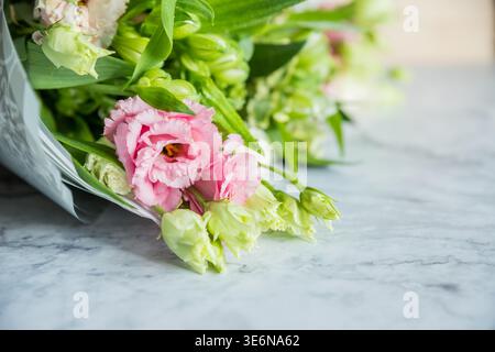 Feiern Sie besondere Anlässe mit einem farbenfrohen Sommerstrauß mit frischen Rosen und Eustoma-Blüten, der ein elegantes und duftendes Blumenarrangement schafft Stockfoto