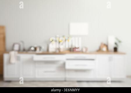 Verschwommener Blick auf weiße Ablagen mit Schubladen und Utensilien im Küchenbereich Stockfoto