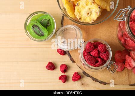 Schüsseln und Gläser mit verschiedenen getrockneten Früchten und Beeren auf hölzernem Hintergrund Stockfoto