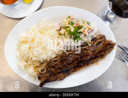 Gegrillte Rinderrippchen Churasko werden mit gekochtem Reis und Salat garniert Stockfoto