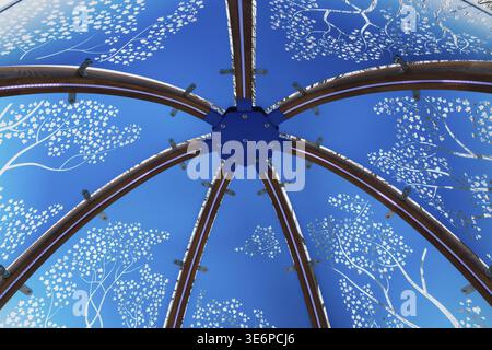 Nahaufnahme von hinterleuchtetem blau getöntem Plexiglas und geschwungenen Holzpaneelen, die mit weißen Ahornblättern im interaktiven Windmotiv verziert sind Stockfoto