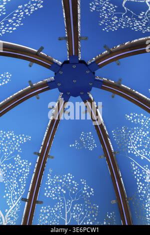 Nahaufnahme von hinterleuchtetem blau getöntem Plexiglas und geschwungenen Holzpaneelen, die mit weißen Ahornblättern im interaktiven Windmotiv verziert sind Stockfoto