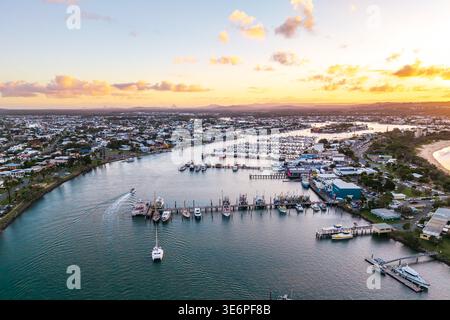 Die Mündung des Mooloolah River am Point Cartwright aus der Vogelperspektive zeigt Boote, Häuser an der Küste und einen Strand bei einem pulsierenden Sonnenuntergang. Stockfoto