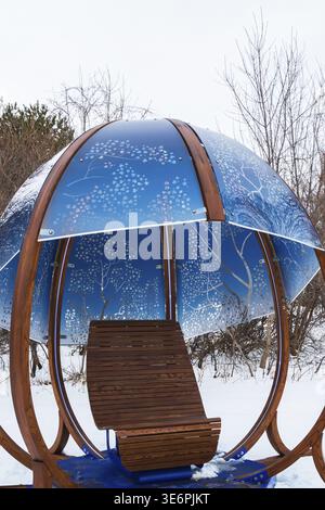 Nahaufnahme von hinterleuchtetem blau getöntem Plexiglas und geschwungenen Holzpaneelen, die mit weißen Ahornblättern im interaktiven Windmotiv verziert sind Stockfoto