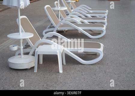 Liegestühle stehen bei sonnigem Wetter am Pool Stockfoto