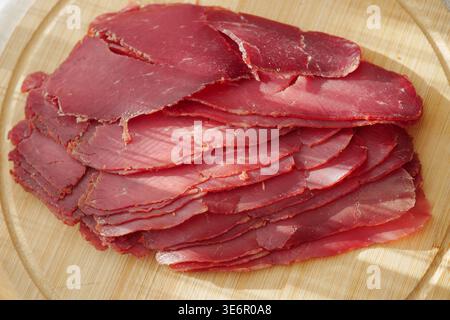 Geräucherte Rindfleischscheiben Auf Holzbrett, Dünn Geschnittenes Deli-Fleisch Für Charcuterie Und Vorspeise Stockfoto