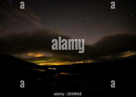 Weite Sicht auf ein Fahrzeug, das unter einem Sternenhimmel mit aurora-Licht in Swaledale geparkt ist Stockfoto