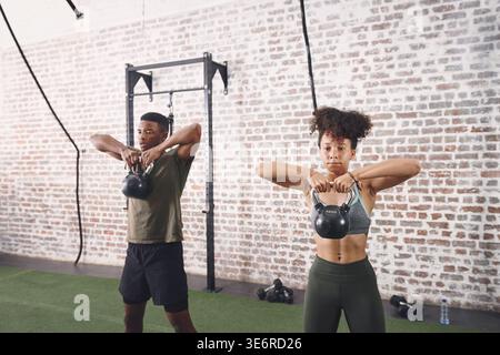 Kettlebells, Workout und Menschen im Fitnessstudio, Fitness für gesundheitliche Vorteile und Herausforderung. Stark, Mann und Frau in der Einrichtung, Ausrüstung für Sport und Stockfoto