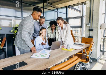 Team aus verschiedenen Hintergründen, das Pläne und Grafiken gemeinsam überprüft Stockfoto