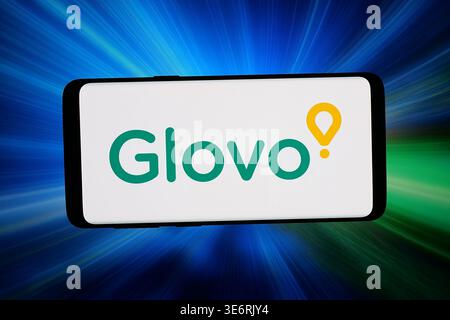 In dieser Fotoabbildung wird das Logo des spanischen Lebensmittellieferanten Glovo auf einem Smartphone vor abstraktem Hintergrund auf dem Computerbildschirm angezeigt. Stockfoto