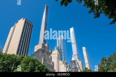 New york, usa, 14. august 2024. Hohe, moderne Wolkenkratzer dominieren die Skyline von manhattan, die hinter grünen Baumkronen des Central Park auf einem klaren klaren klaren Himmel aufragt Stockfoto