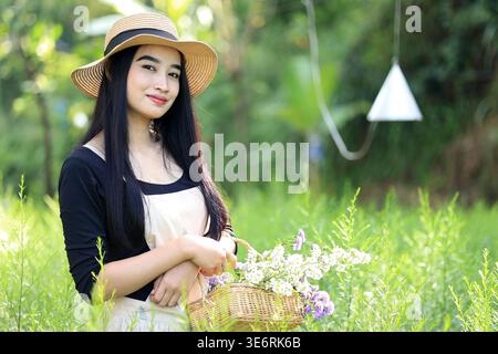 Junge asiatische Frau, die Purpur und Weiße Blume erntet Stockfoto