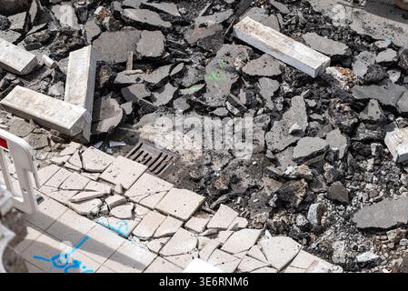 Beschädigte Straßenoberfläche mit Schutt und Metallabfluss das Konzept der Stadterneuerung Stockfoto