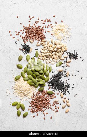 Mischung aus Samen auf weißem Hintergrund, Draufsicht, Textur. Gesunde Ernährung Inhaltsstoffe Textur. Kürbiskerne, schwarzes und weißes Sesam, Chia, Sonnenblumenkerne Stockfoto