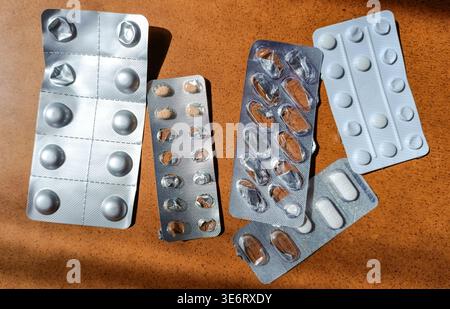 Fünf gebrauchte Blisterpackungen mit Pillen auf hölzernem Tisch, Ansicht von der Tischplatte Stockfoto