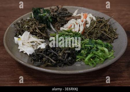 Verschiedene koreanische Beilagen mit Gemüse auf einem rustikalen Teller Stockfoto