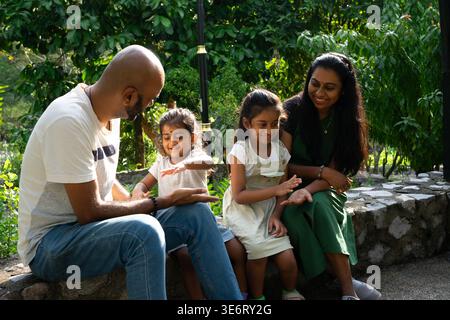 Indische Familienverbände, Eltern und Töchter spielen einfache Spiele in einem üppigen Garten Stockfoto