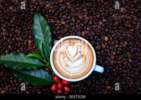 Ein kommerzielles Studio-Bild von einem Latte mit frischen Kaffeeblättern und roten Drupes, die die erstklassige Kaffeekultur und Kaffeeproduktion symbolisieren. Stockfoto