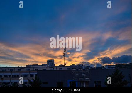 Hochauflösendes Foto eines Mobilfunkturms, der vor einem dramatischen Sonnenuntergangshimmel steht. Das Bild zeigt die dunkle Silhouette des Fernmeldemastkoordinators Stockfoto