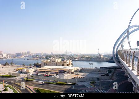 Panoramablick auf Dubai Creek mit moderner Infinity Bridge und traditioneller arabischer Architektur unter hellem Himmel, VAE. Stockfoto
