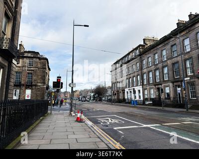 Edinburgh, Schottland, Großbritannien - 16. Februar 2026: Leerer Atholl Place Bürgersteig und Straßenbahnlinie gesäumte Straße, umrahmt von georgianischen Steinhäusern unter einer bewölkten Winde Stockfoto