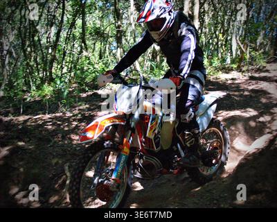 Geländegängige Enduro-Motorradfahrer fahren mit einem KTM-Dirt-Bike durch Waldwege und schlammiges Gelände in Jeffreys Bay. Südafrika Stockfoto