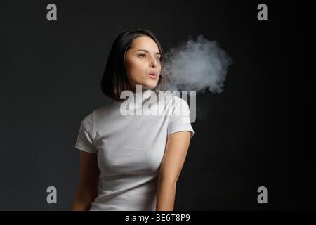Junge Frau, die dampft und von der Kamera wegblickt Stockfoto