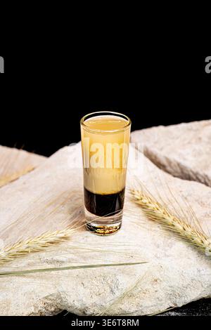 Nahaufnahme des Schichtenfotos mit Karamelllikör, Schokolade, Vanillelikör, Karamell-Popcorn und fliegendem Kakaopulver auf Holzstuhl. Süßes Getränk. Stockfoto