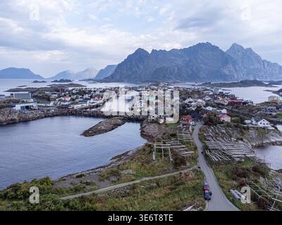 Blick aus der Vogelperspektive auf ein malerisches Fischerdorf inmitten der zerklüfteten Lofoten-Inseln, mit dem Meer, das die gedämpften Töne des Himmels reflektiert, Henningsvær, Nordlan Stockfoto
