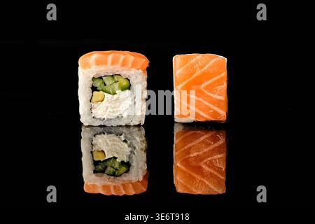 Zwei Sushi-Brötchen aus Philadelphia in frischen Lachs mit Frischkäse-, Gurken- und Avocadofüllung, eines mit Querschnitt im Inneren, isoliert Stockfoto