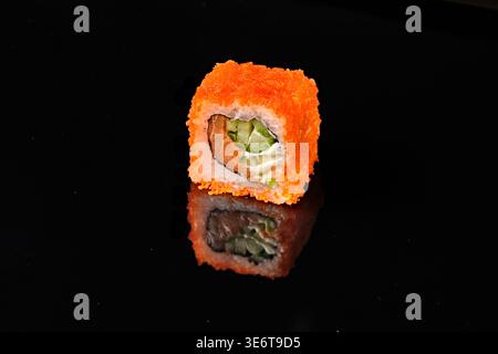 Zwei kalifornische Sushi-Brötchen, bedeckt mit orangenem tobiko fliegendem Fischrogen, mit Lachs, Frischkäse und Avocadofüllung, eines mit Querschnitt interi Stockfoto