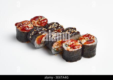 Acht Maki-Sushi-Brötchen in Nori-Algen mit Meeresfrüchten und Gemüsefüllung, garniert mit dunkler Teriyaki-Sauce, roter Gewürzsauce und Sesamsamen, Stockfoto