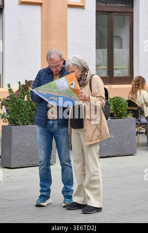 Mallorca. Spanien - 08. April 2026: Seniorenpaar, die sich eine Touristenkarte von Palma anschauen, während sie während ihres Urlaubs auf einem historischen Stadtplatz stehen. Stockfoto
