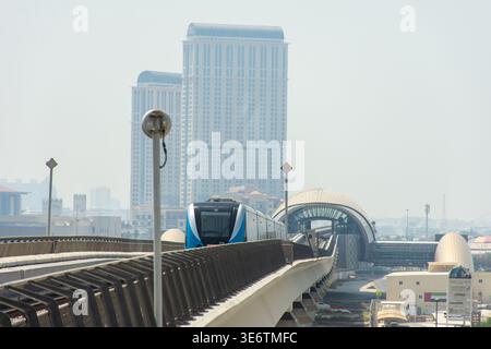 Vorderansicht eines modernen, automatisierten, erhöhten U-Bahn-Zuges, der sich auf Gleisen durch eine Skyline der Stadt in Dubai, VAE, nähert. Stockfoto