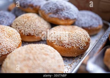Frische Sesambrötchen und Puderzucker-Donuts auf Backblech. Hochwertige Fotos Stockfoto