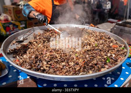 Street Food-Anbieter kochen geschnittenes Dönerfleisch auf einer großen Pfanne. Hochwertige Fotos Stockfoto