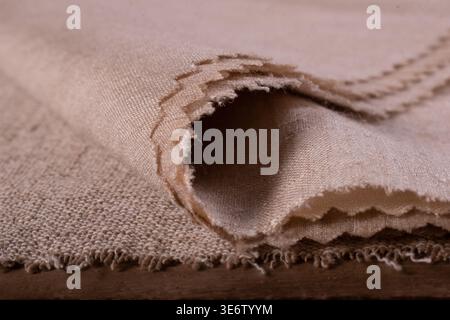 Nahaufnahme von gefaltetem beigem Matka-Seidenmuster mit ausgefransten Kanten und sichtbarer Webstruktur für die Textil- und Modebranche Stockfoto