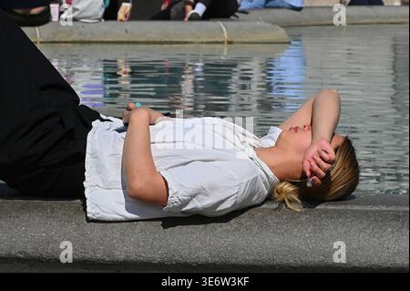 LONDON, GROSSBRITANNIEN. April 2026. Eine Frau liegt am Rande eines Springbrunnens am Trafalgar Square, während Londoner nach einer unsaisonalen Hitzewelle im April suchen. Das Met Office hat heute Temperaturen von 26 °C aufgezeichnet, was es zum bisher heißesten Tag des Jahres und zum wärmsten Anfang April seit sechs Jahren macht. Foto: Ehimetalor Unuabona/Alamy Live News. Stockfoto