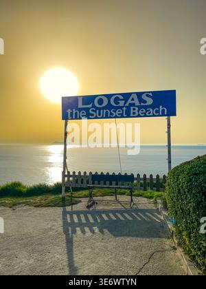 Schild für Logas Sunset Beach bei Sonnenuntergang in Peroulades, Korfu. Malerischer Blick auf die goldene Sonne über dem Ionischen Meer, Griechenland, 13. Juli 2023 Stockfoto